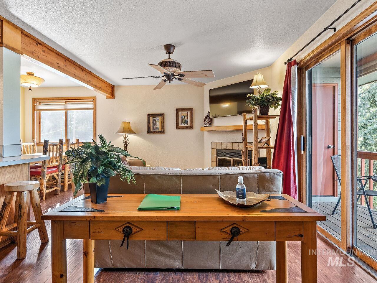 Living Room featuring wood finished floors, a ceiling fan, plenty of natural light, beam ceiling, and a textured ceiling