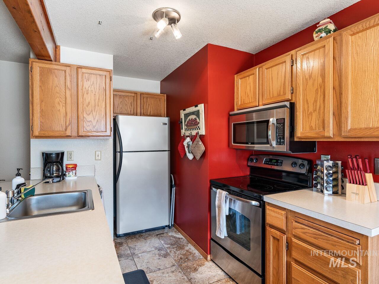 Kitchen with appliances with stainless steel finishes, light countertops, and a textured ceiling