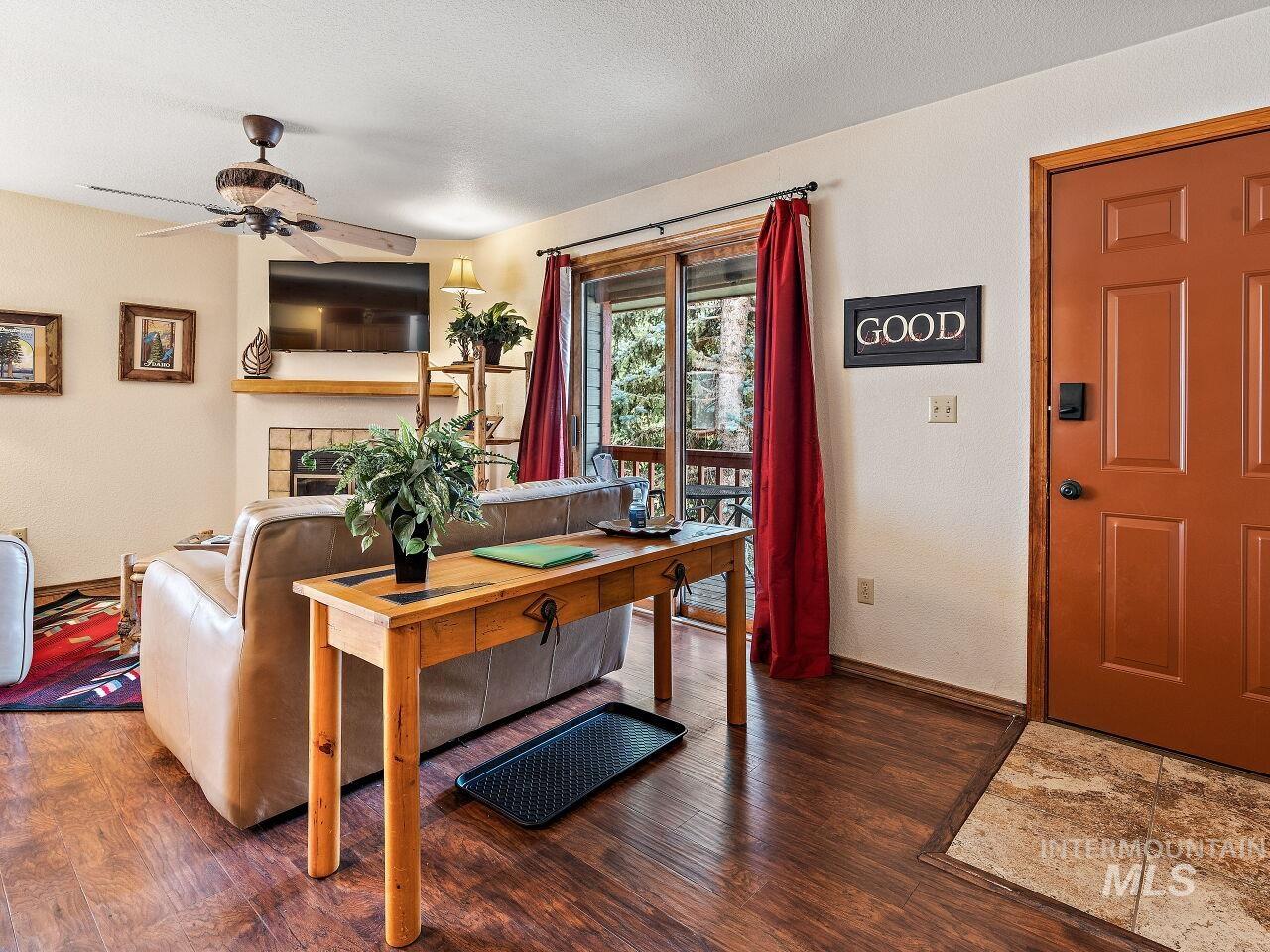 Living room with wood finished floors, a ceiling fan, and a tiled fireplace