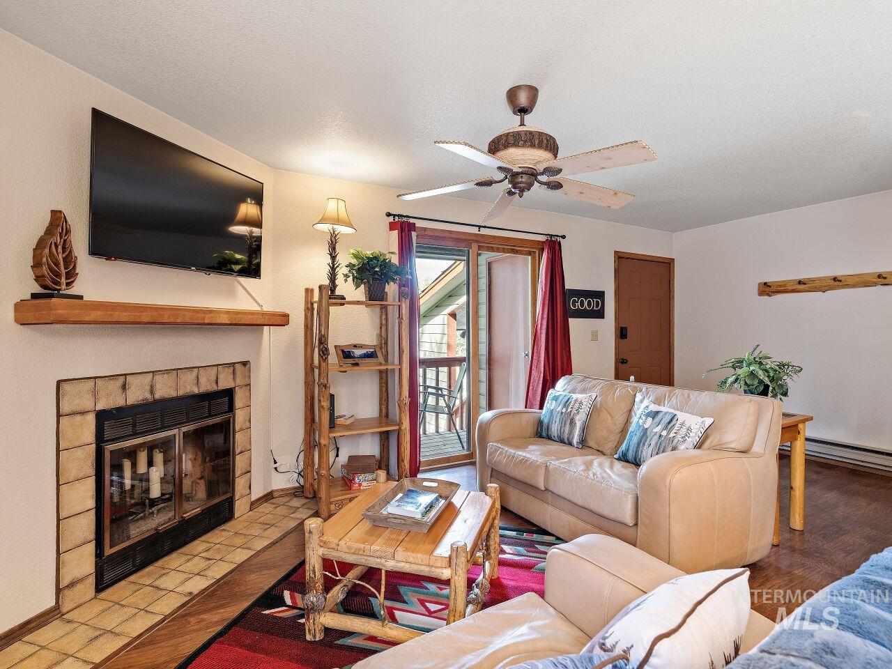 Living area featuring a tiled fireplace and ceiling fan