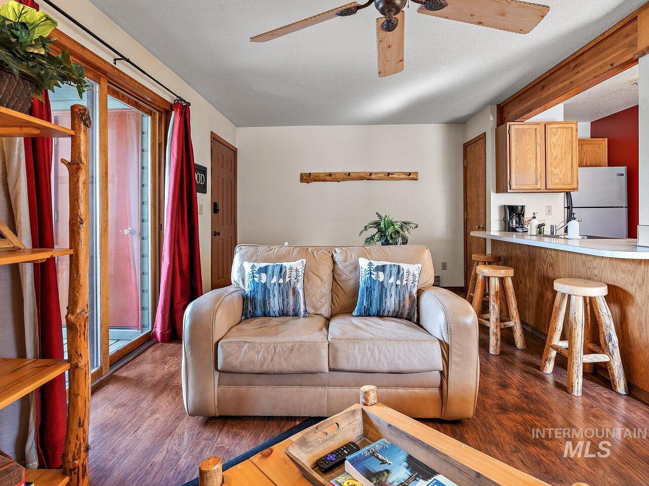Living room with ceiling fan, dark wood-style floors, and a textured ceiling