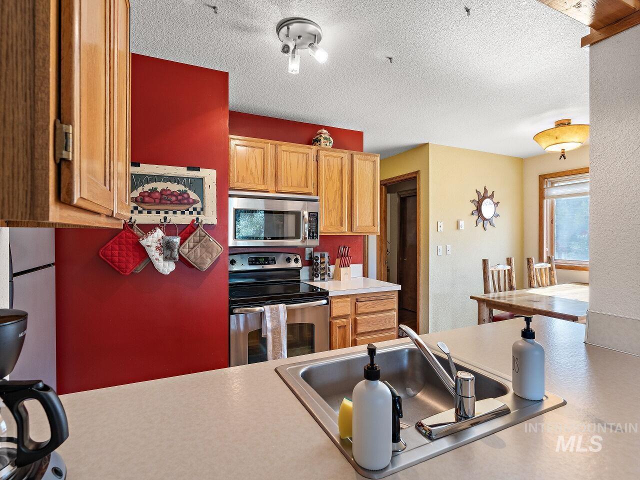 Kitchen featuring stainless steel appliances, light countertops, and a textured ceiling