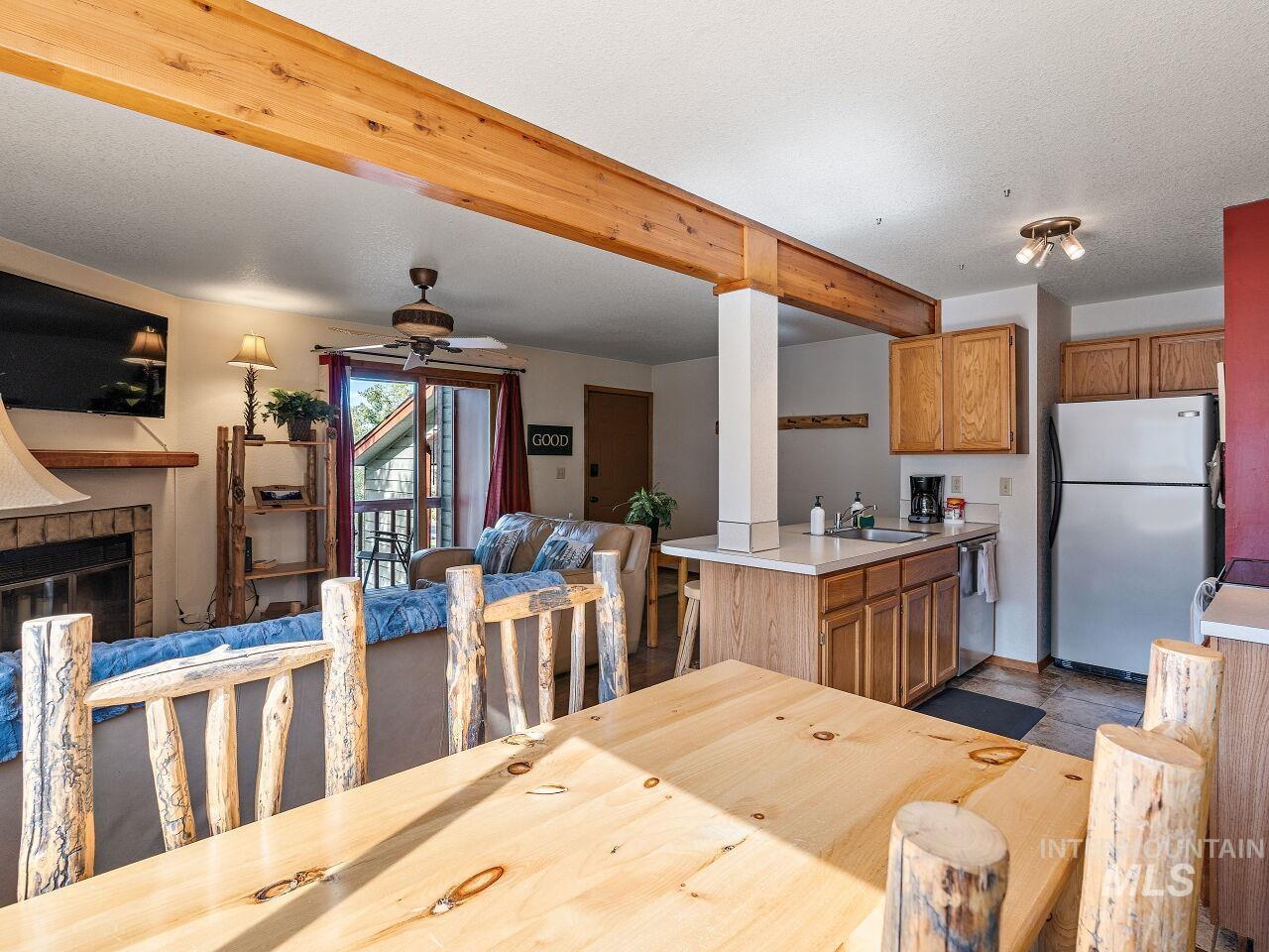 Dining area with a ceiling fan, a glass covered fireplace, and beam ceiling