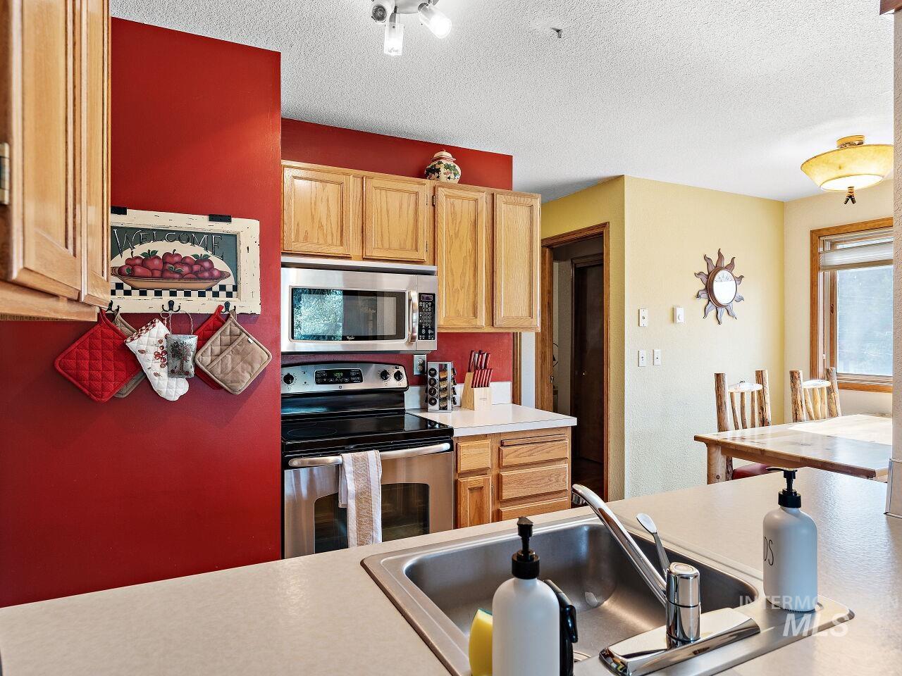 Kitchen with appliances with stainless steel finishes, light countertops, a textured ceiling, and light brown cabinetry