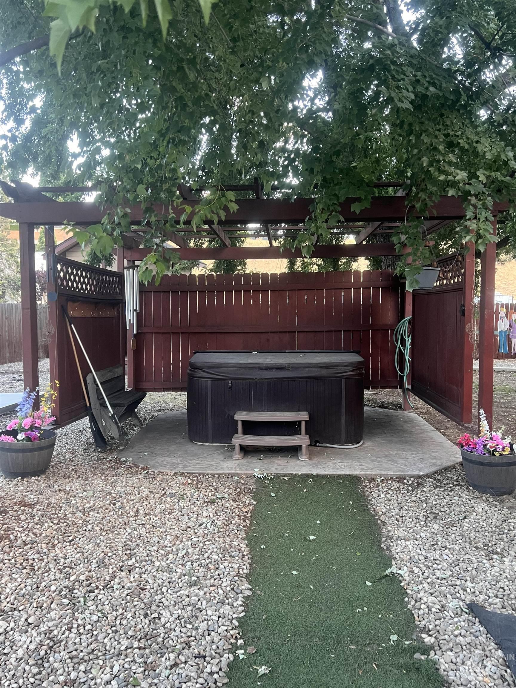 Outdoor spa area featuring a wooden pergola, privacy fencing, and a concrete pad