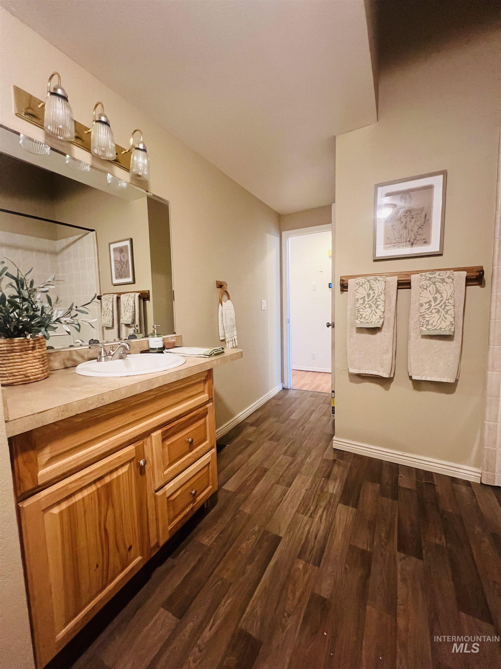 Bathroom featuring a wood-finish vanity with an integrated sink, a large wall mirror, and a three-light fixture. Accessible walk-in tub that could be converted to a tub/shower combo.