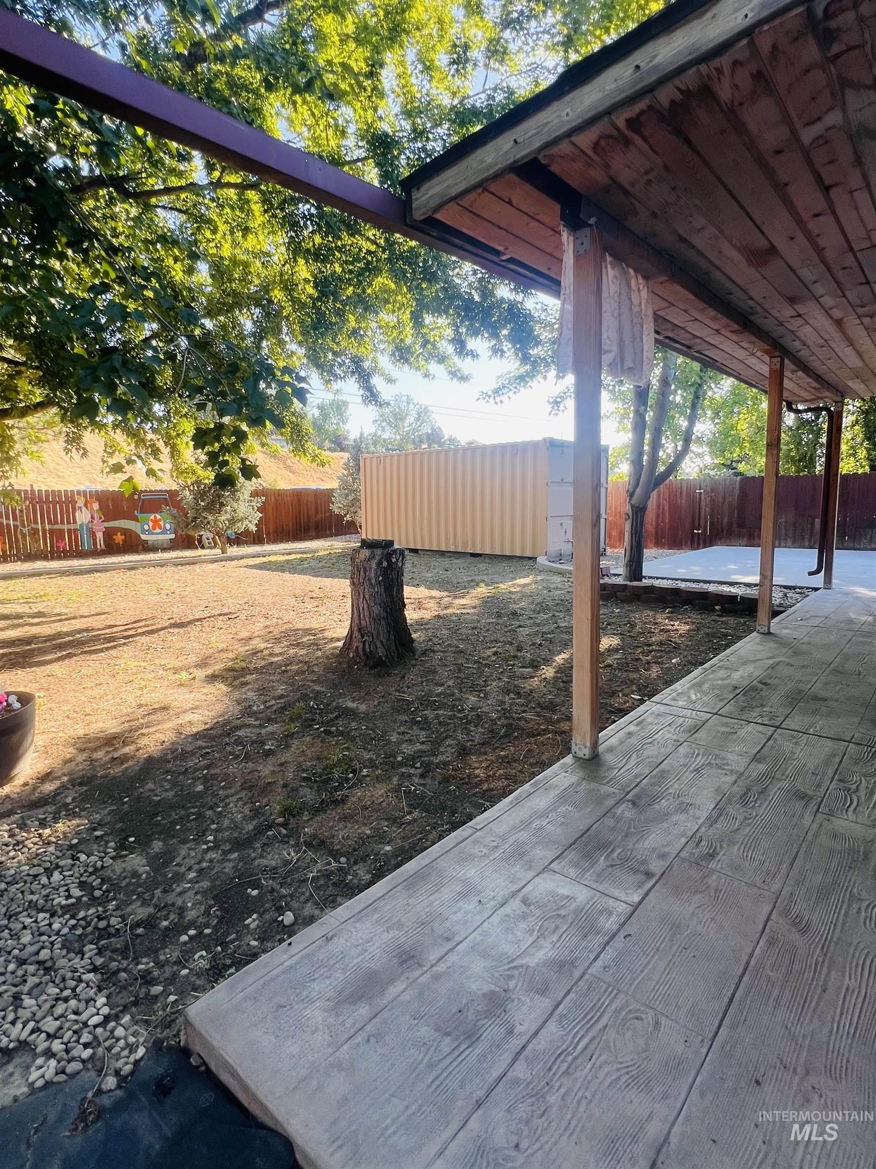 Expansive outdoor living area featuring a covered patio with wood-finish ceiling, stamped concrete flooring, and substantial wooden support beams