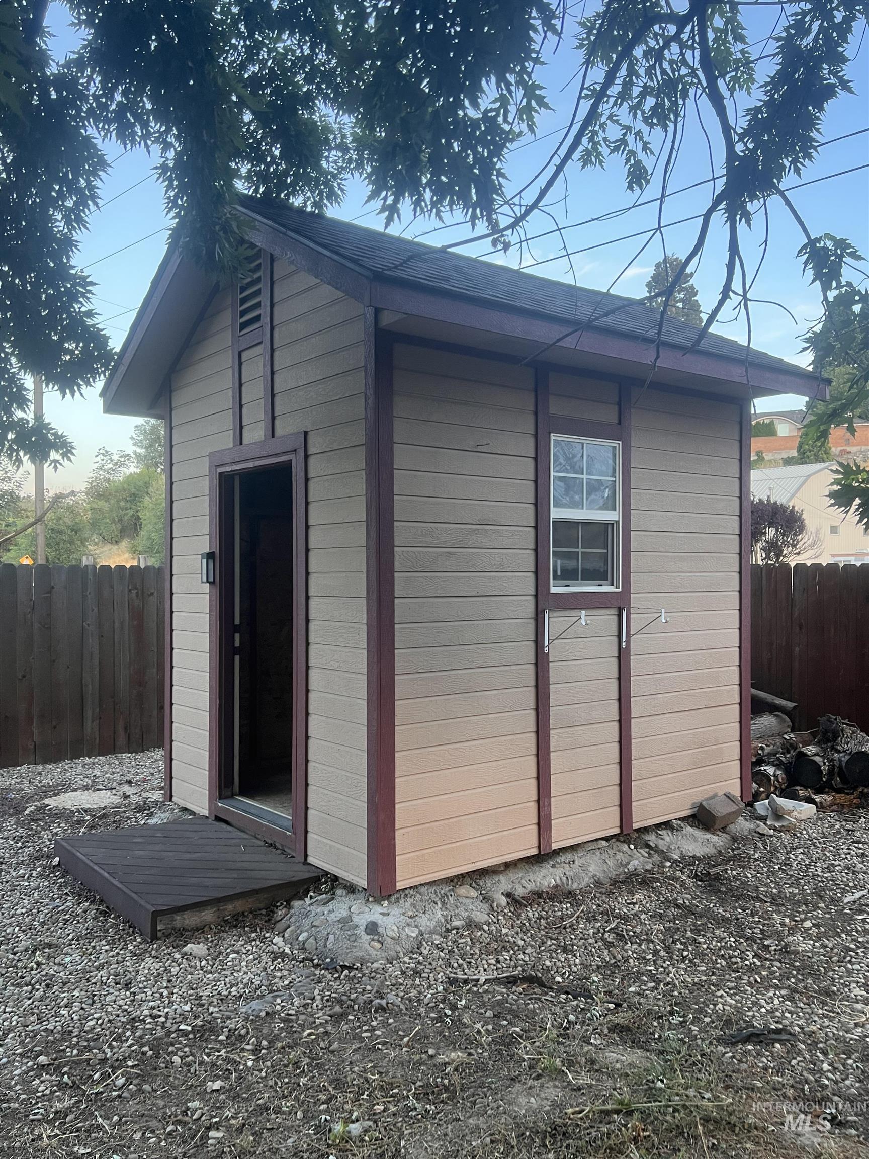 Storage shed featuring horizontal panel siding, an asphalt shingle roof, and a single-pane window
