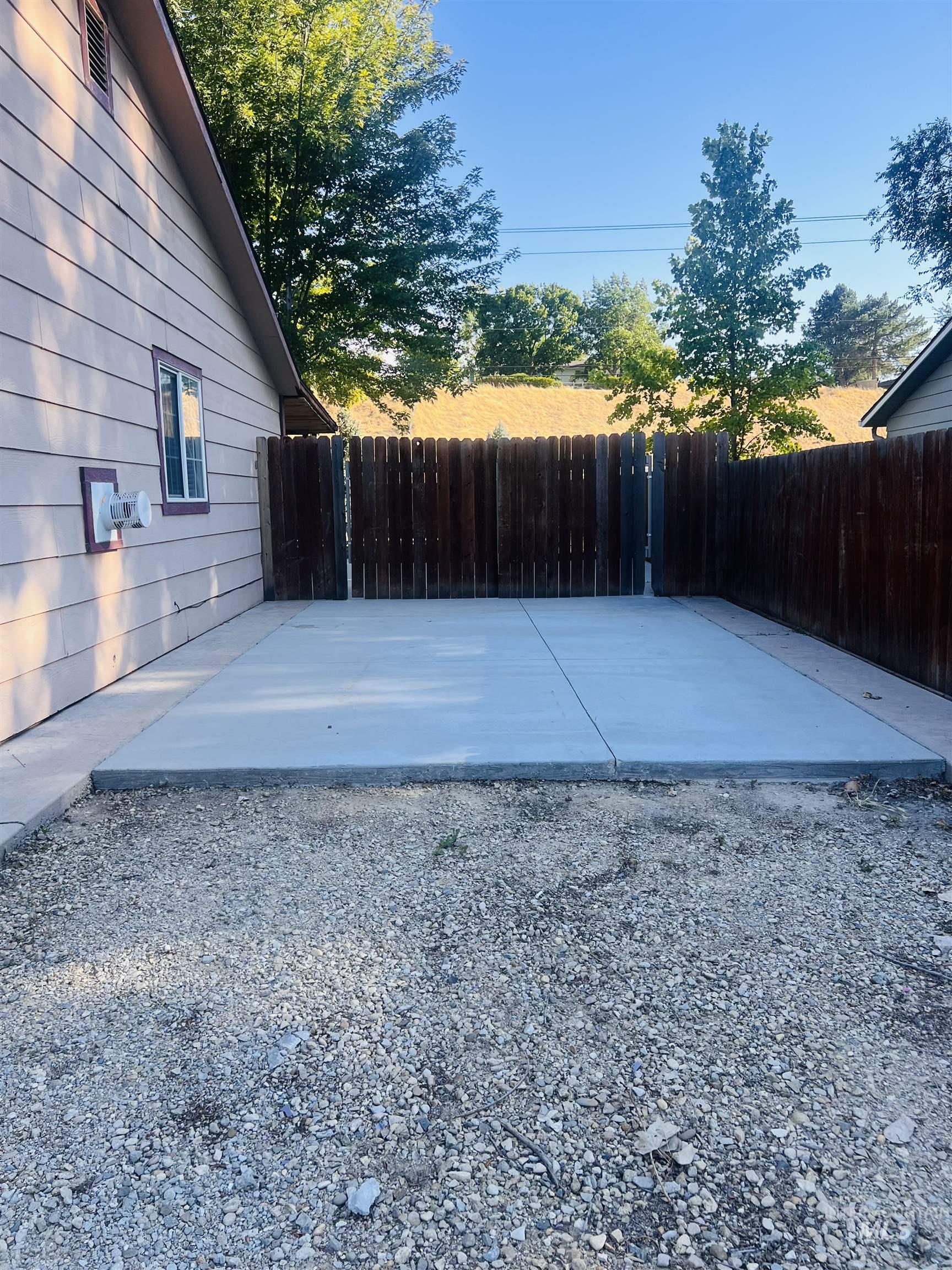 Rear concrete patio with a privacy fence and gravel ground cover