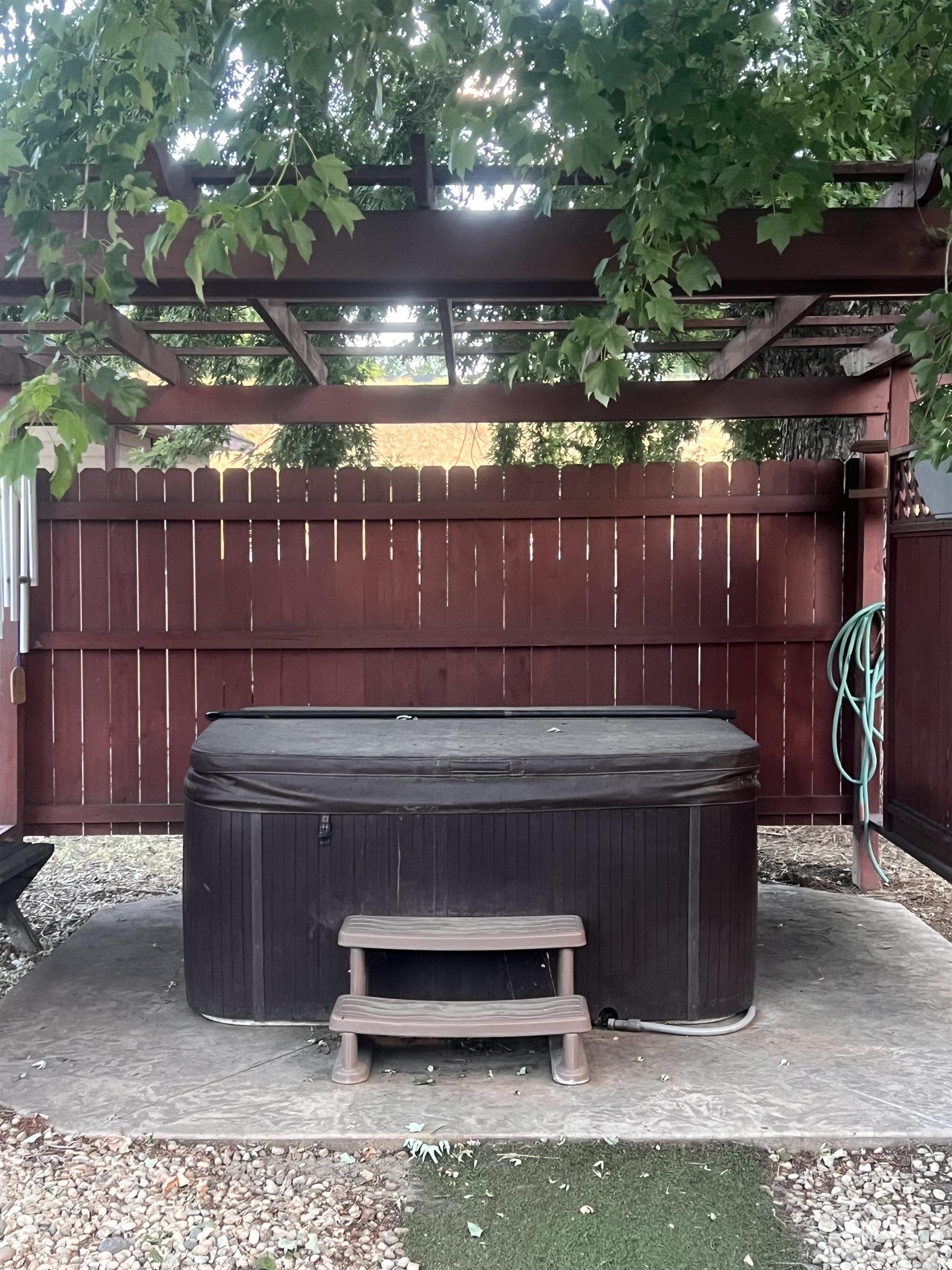 Outdoor spa with a protective cover, set on a concrete pad with two-step access.  Working