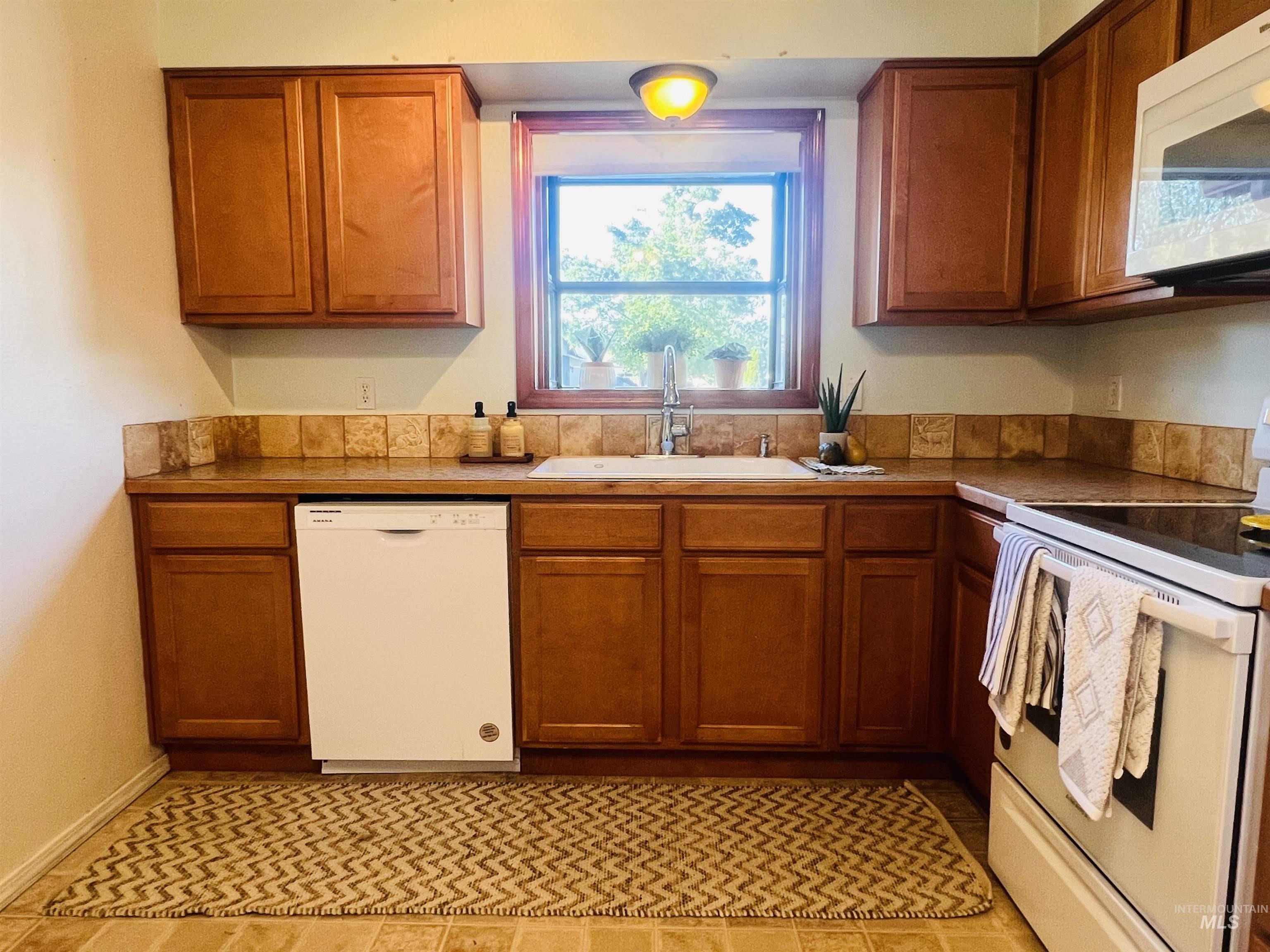 Kitchen featuring wood-finish cabinetry, tile countertops, and a coordinating tile backsplash
