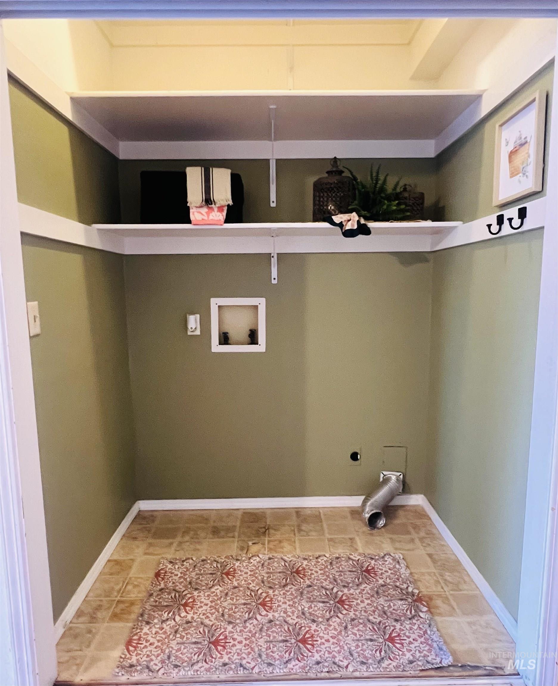 Dedicated utility alcove featuring dual built-in shelving, durable vinyl flooring, and a neutral wall color