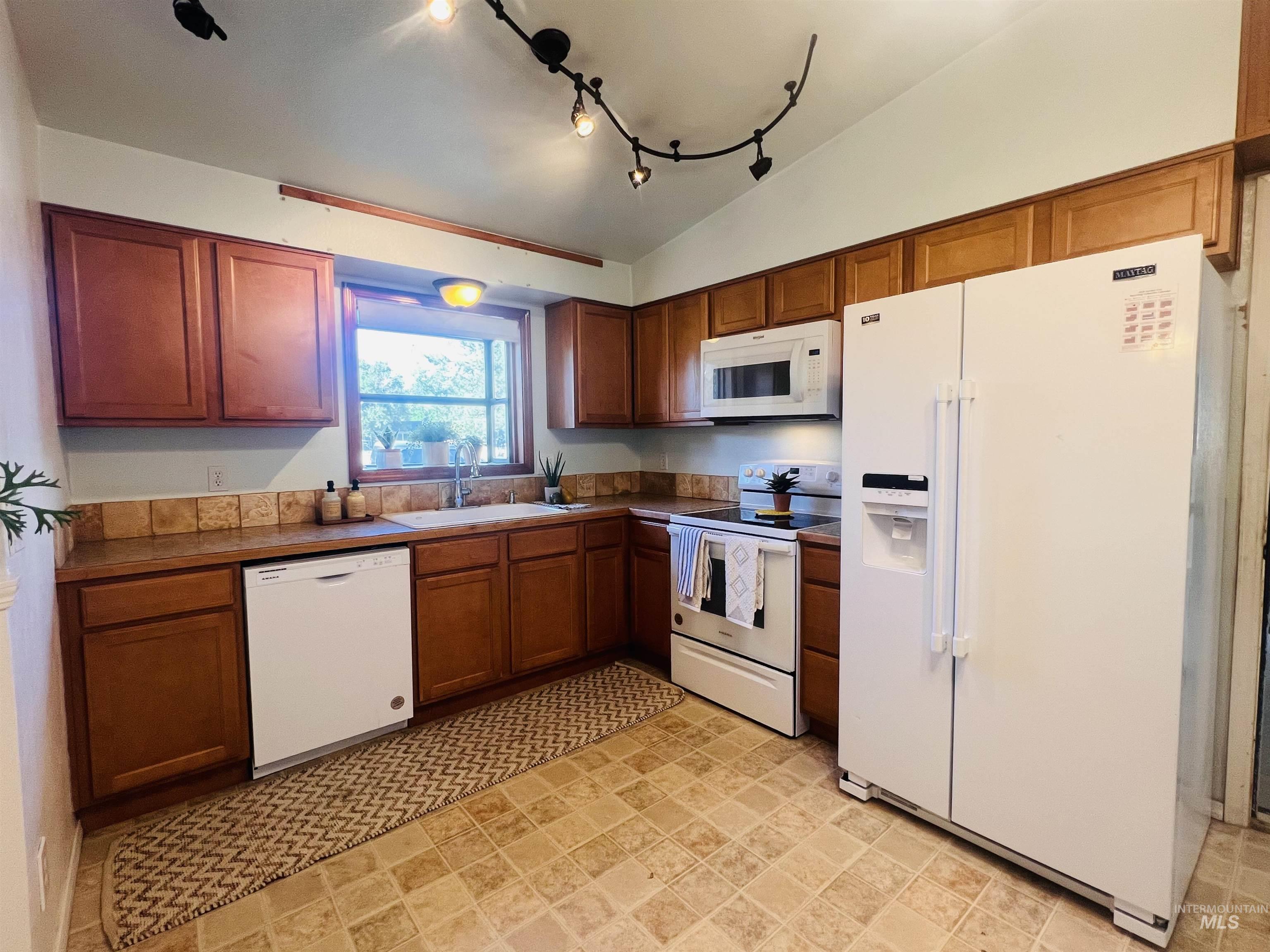 Kitchen featuring medium-tone wood cabinetry, tile countertops, a tile backsplash, and track lighting