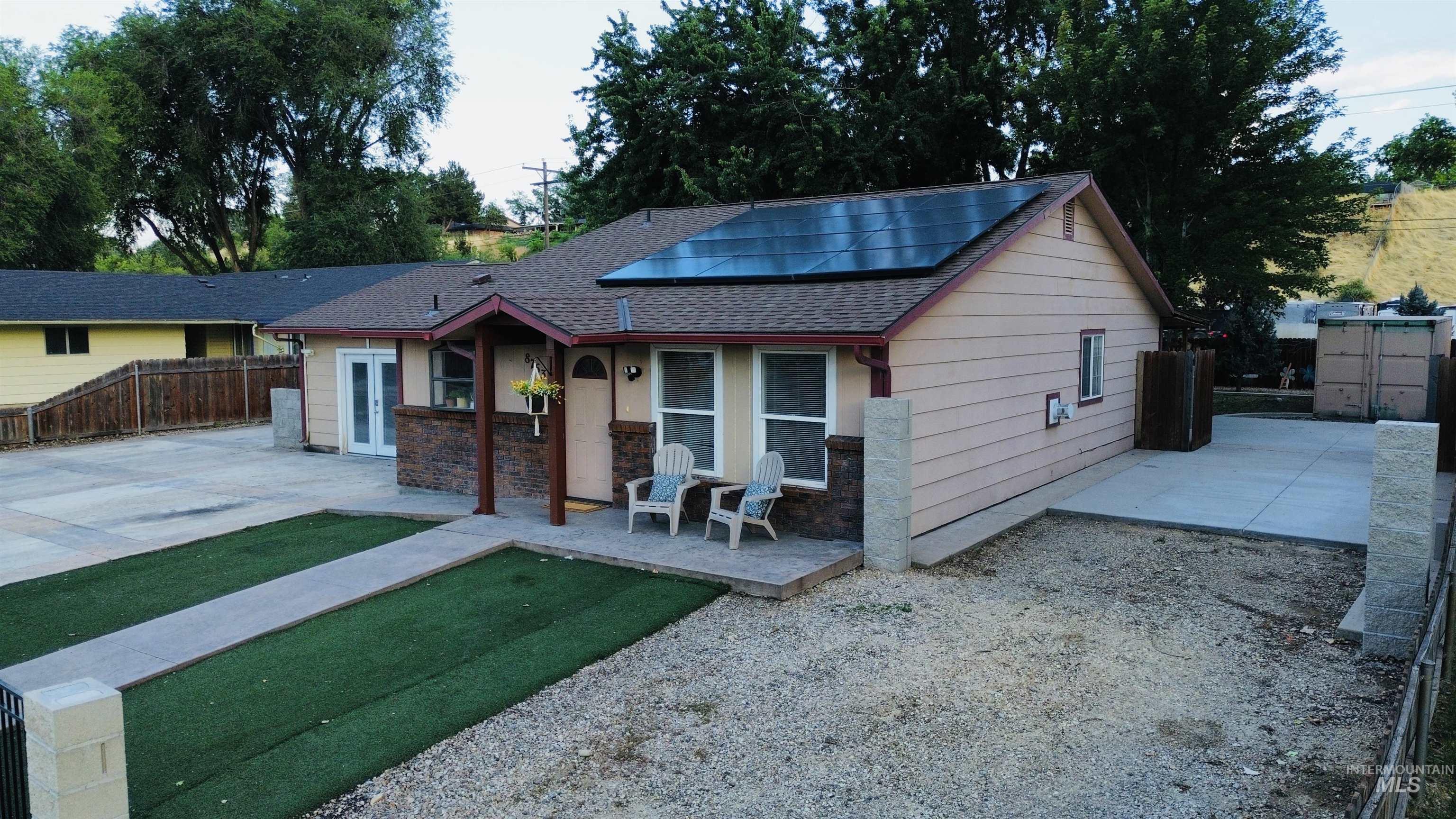 Single-story residence featuring a covered entry, stone veneer accents, and solar panels