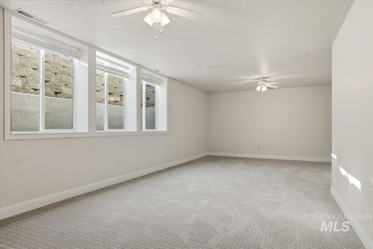 Unfurnished room with a ceiling fan, light colored carpet, and a textured ceiling