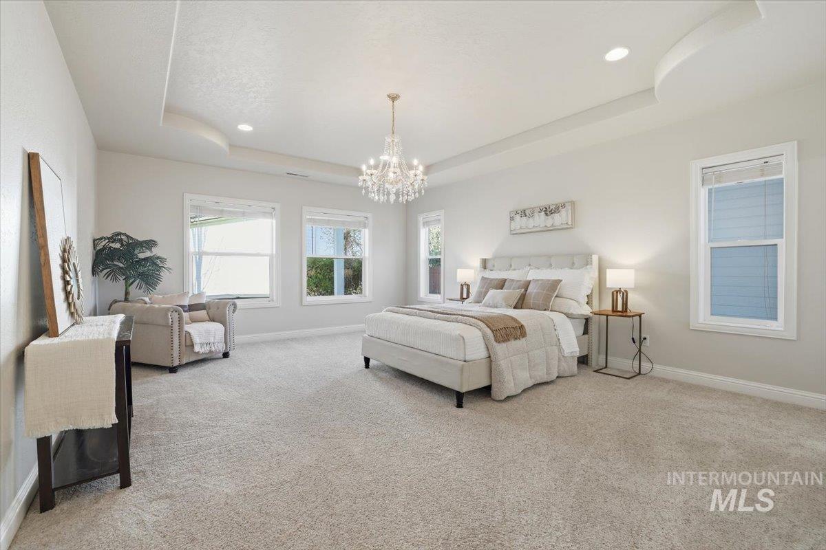 Bedroom with a raised ceiling, a chandelier, light colored carpet, and recessed lighting