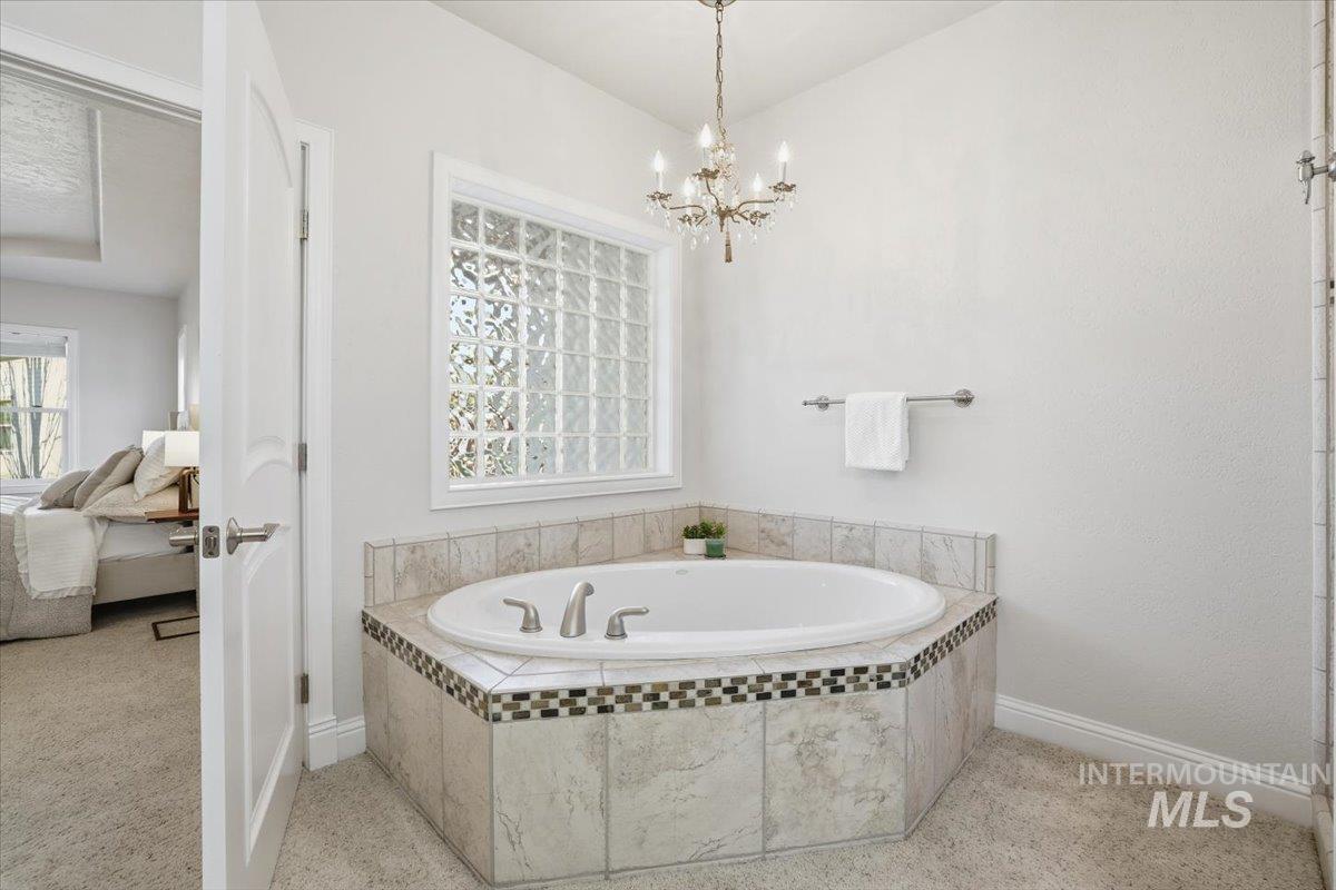 Ensuite bathroom featuring a bath and a chandelier