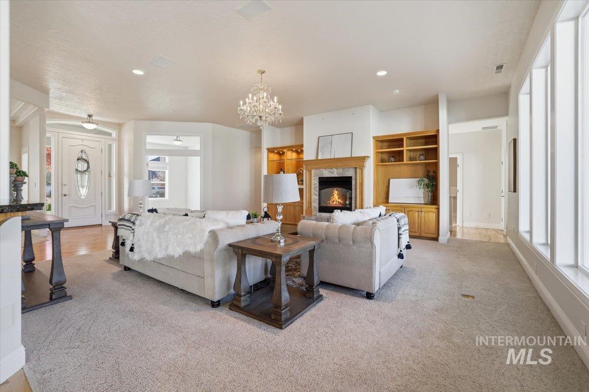 Living room featuring a premium fireplace, plenty of natural light, a chandelier, recessed lighting, and light carpet