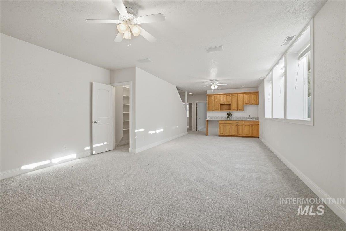 Unfurnished living room with light colored carpet, a textured ceiling, and a ceiling fan