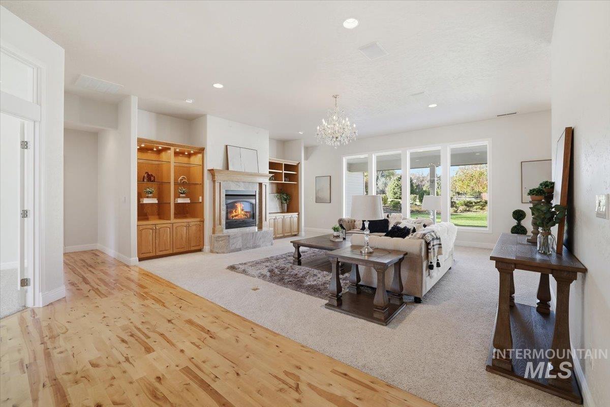 Living area with a tiled fireplace, light wood-style floors, a chandelier, recessed lighting, and light colored carpet