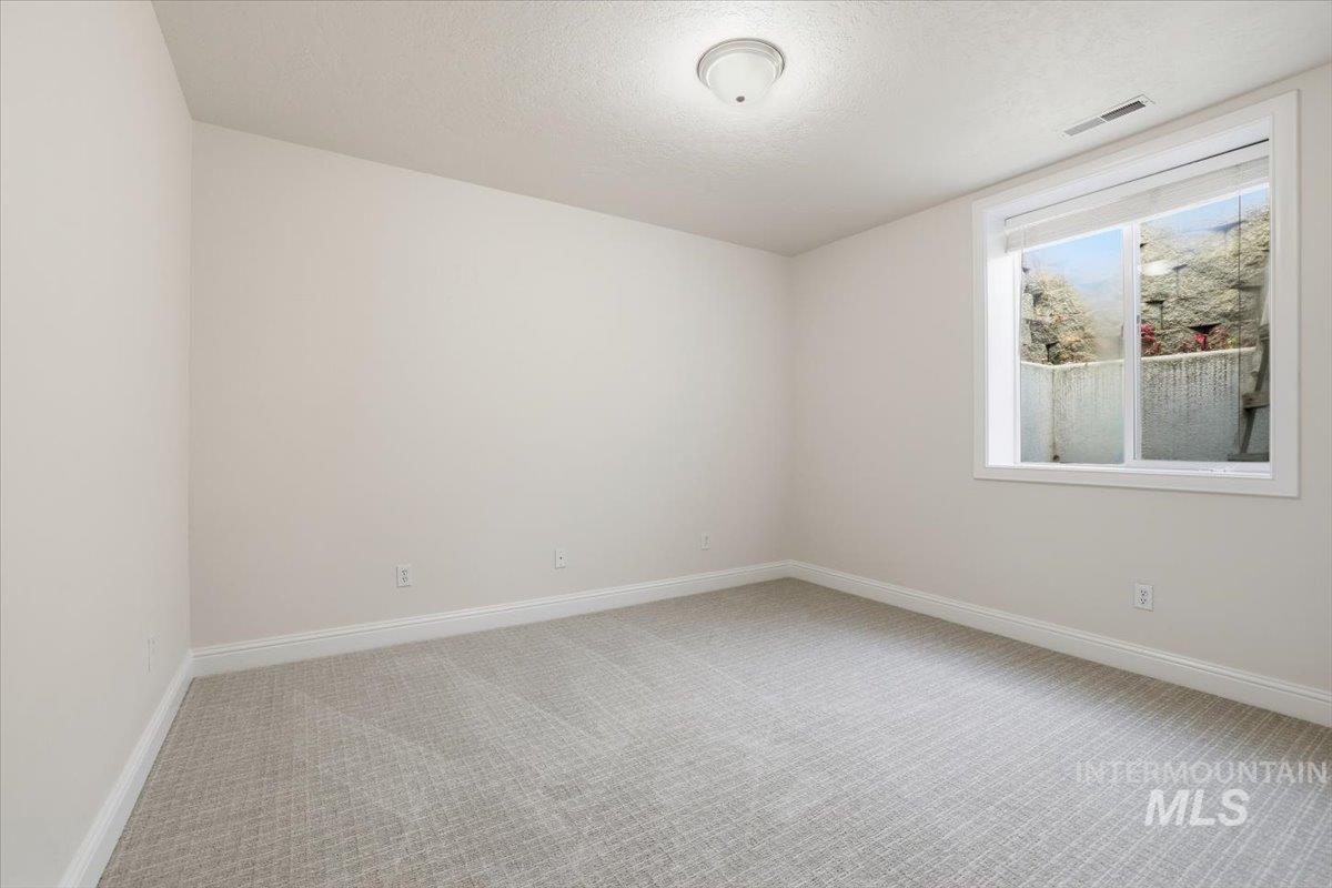 Unfurnished room featuring light colored carpet and a textured ceiling