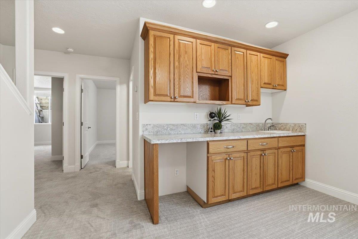 Kitchen with light colored carpet, brown cabinetry, and recessed lighting