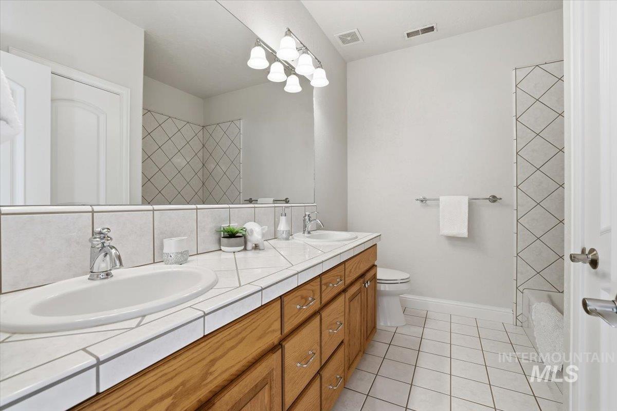 Bathroom featuring light tile patterned floors, double vanity, and a chandelier