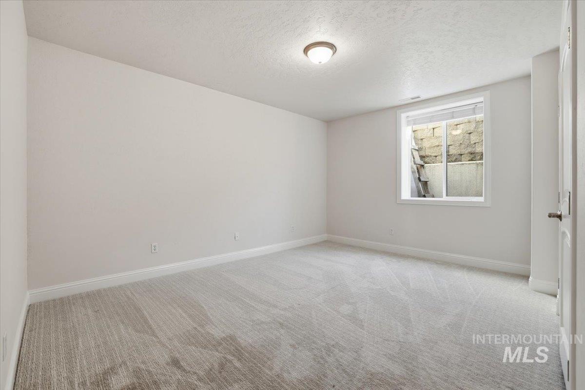 Unfurnished room featuring light carpet and a textured ceiling