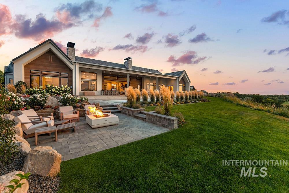 Back of property with a patio, a chimney, a lawn, and a fire pit