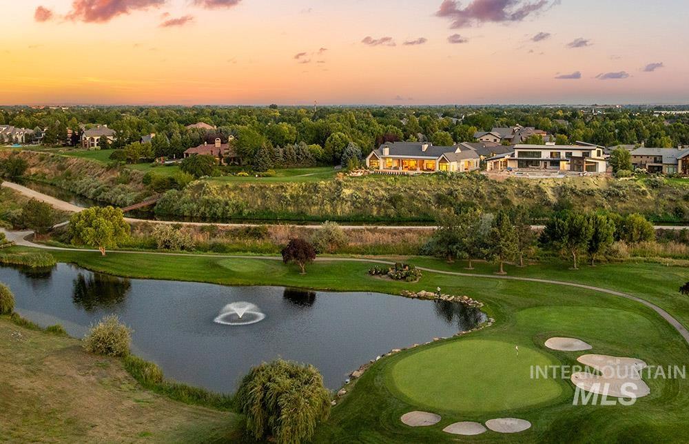 Aerial view at dusk of a water view, view of wooded area, a residential view, and view of golf course