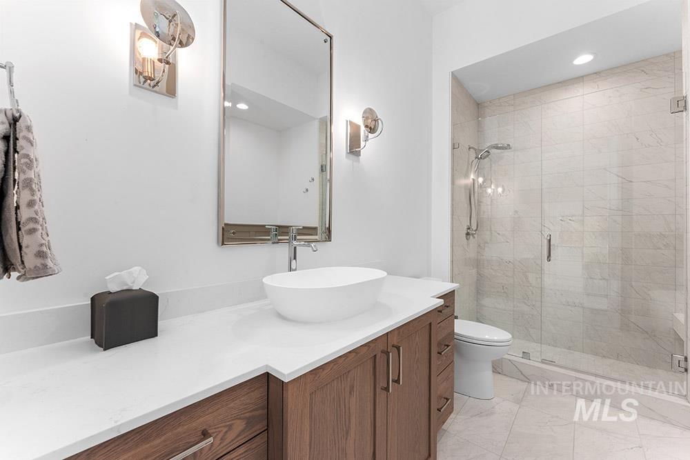 Bathroom featuring vanity, a stall shower, recessed lighting, and marble look tile flooring