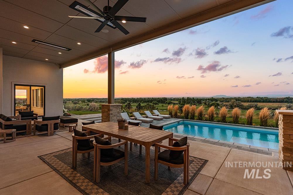 Pool at dusk with a ceiling fan, a patio area, an outdoor pool, and outdoor dining area