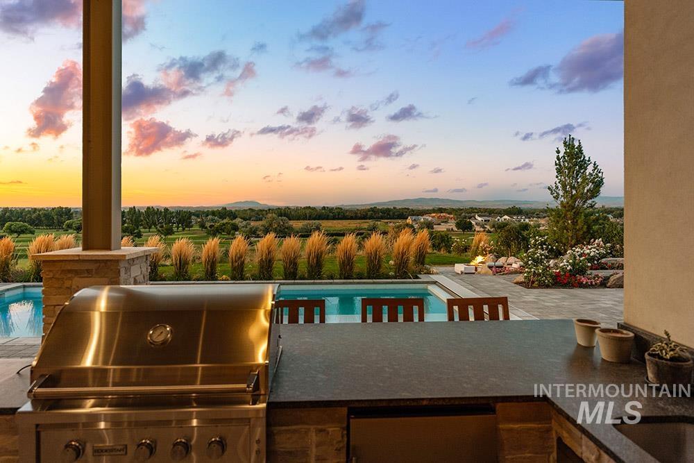 Pool at dusk featuring an outdoor kitchen, an outdoor pool, and a patio area
