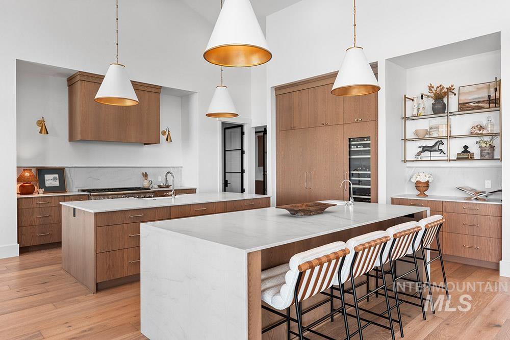 Kitchen featuring a large island, modern cabinets, light wood-style flooring, and a high ceiling