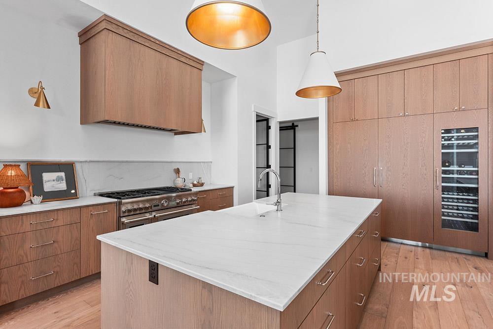 Kitchen featuring an island with sink, light wood-type flooring, range with two ovens, and a barn door