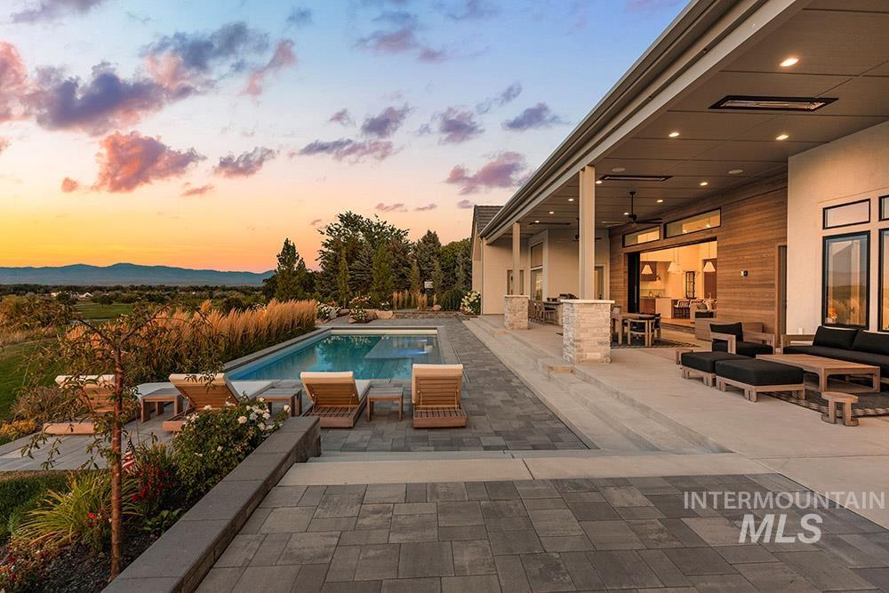 Pool at dusk with a patio area, an outdoor living space, and an outdoor pool