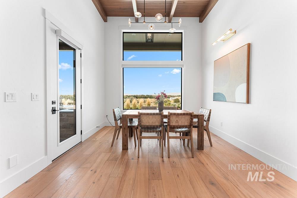 Dining area featuring a wooden ceiling with exposed beams, light wood-style flooring, and a high ceiling