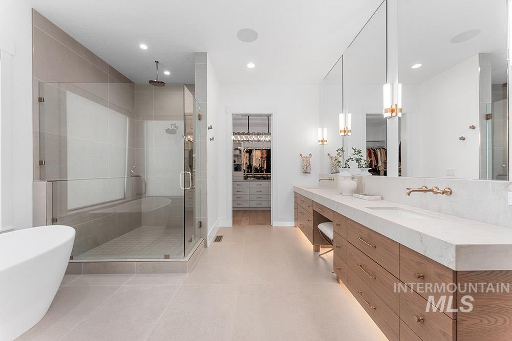 Bathroom featuring a spacious closet, a shower stall, double vanity, tile patterned floors, and a soaking tub