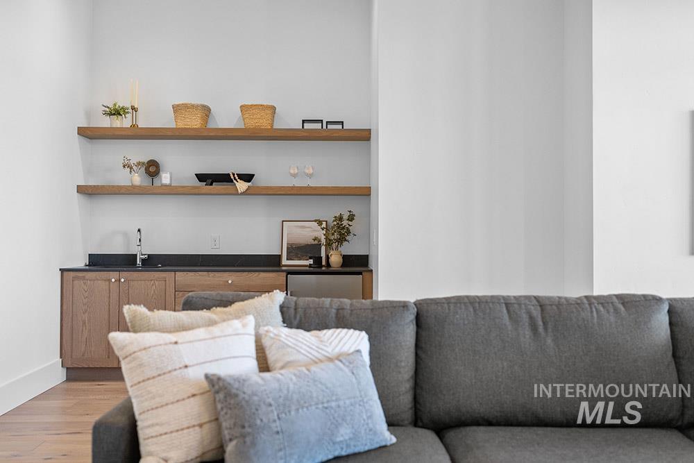 Living room with light wood finished floors and bar with sink