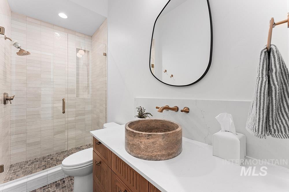 Bathroom with a shower stall, vanity, and recessed lighting