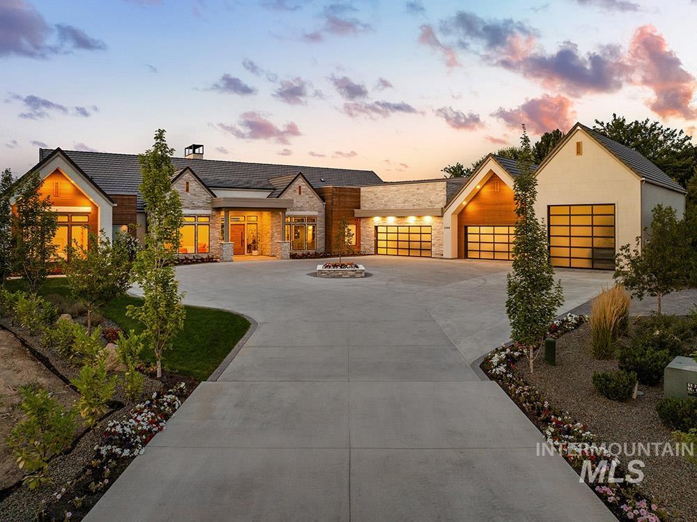 View of front of property featuring stone siding, curved driveway, and an attached garage