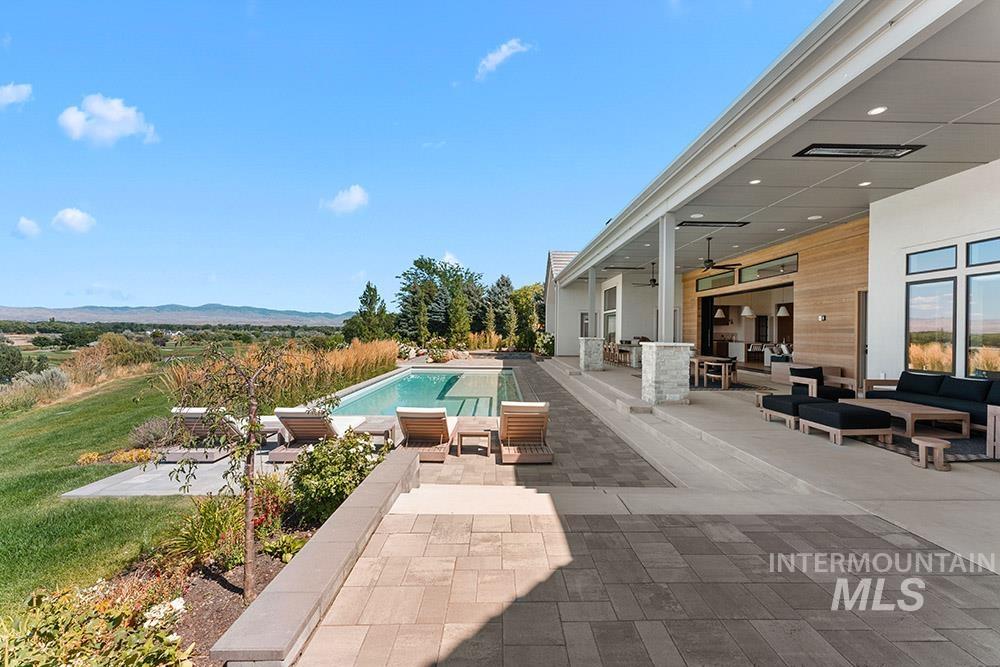 Outdoor pool featuring outdoor lounge area, a ceiling fan, a patio area, and a mountain view
