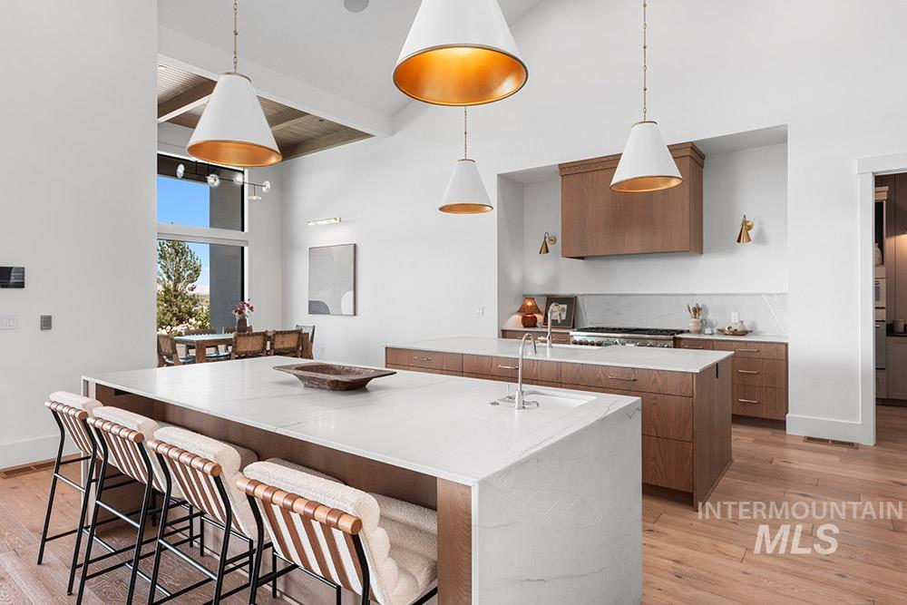 Kitchen with a large island, brown cabinets, modern cabinets, light wood-type flooring, and a towering ceiling