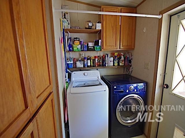 Dedicated laundry area featuring a top-load washing machine, a front-load dryer, and overhead wood-finish cabinetry
