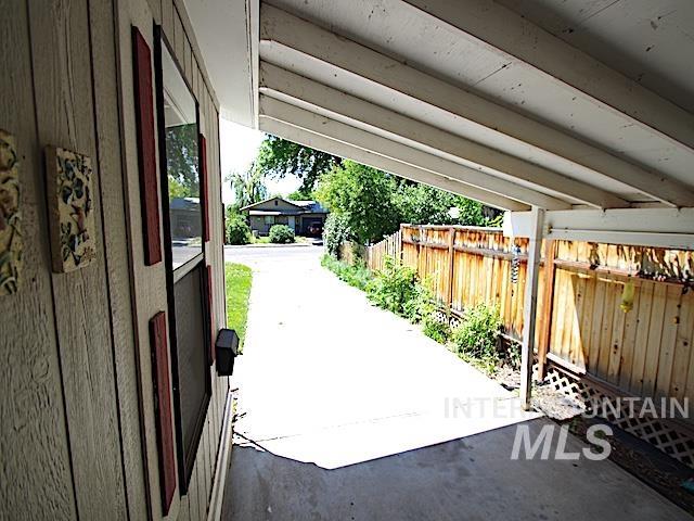 Covered carport with a concrete driveway, wood privacy fence, and horizontal siding