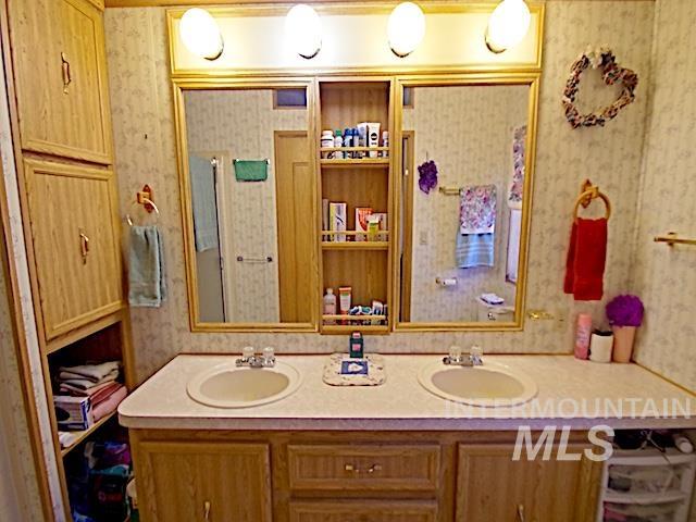 Bathroom featuring a dual vanity with laminate countertops and wood-finish cabinetry
