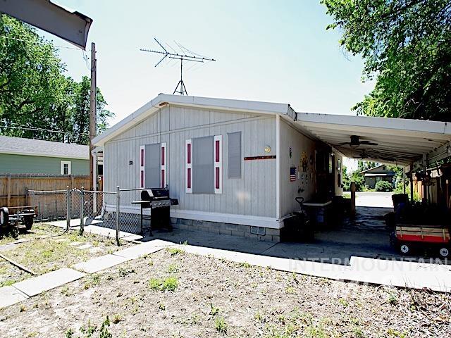 Light-colored siding exterior with a covered carport featuring a ceiling fan