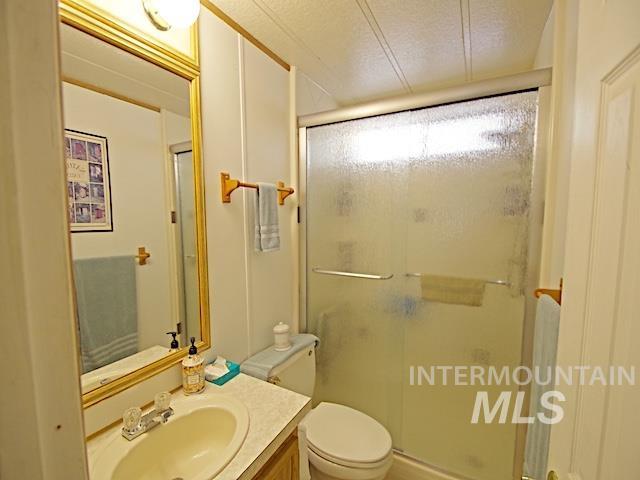 Bathroom featuring a vanity with an integrated sink, a framed mirror, and a shower with sliding glass doors