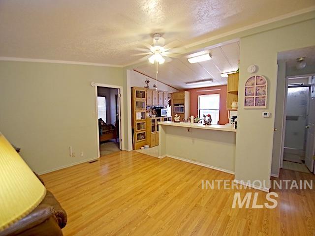 Open concept living space featuring wood-finish flooring, light green wall tones, and crown molding