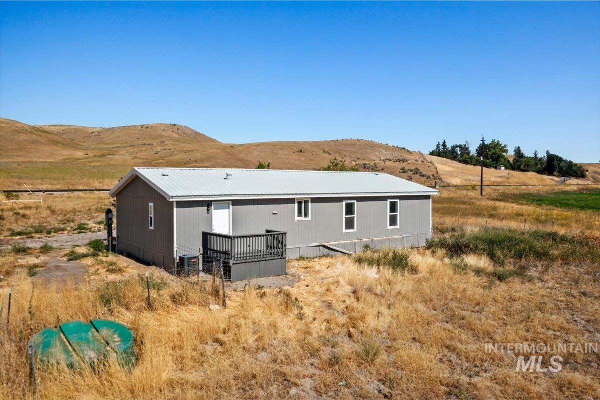 Rear view of property with a deck with mountain view, a metal roof, and a view of rural / pastoral area